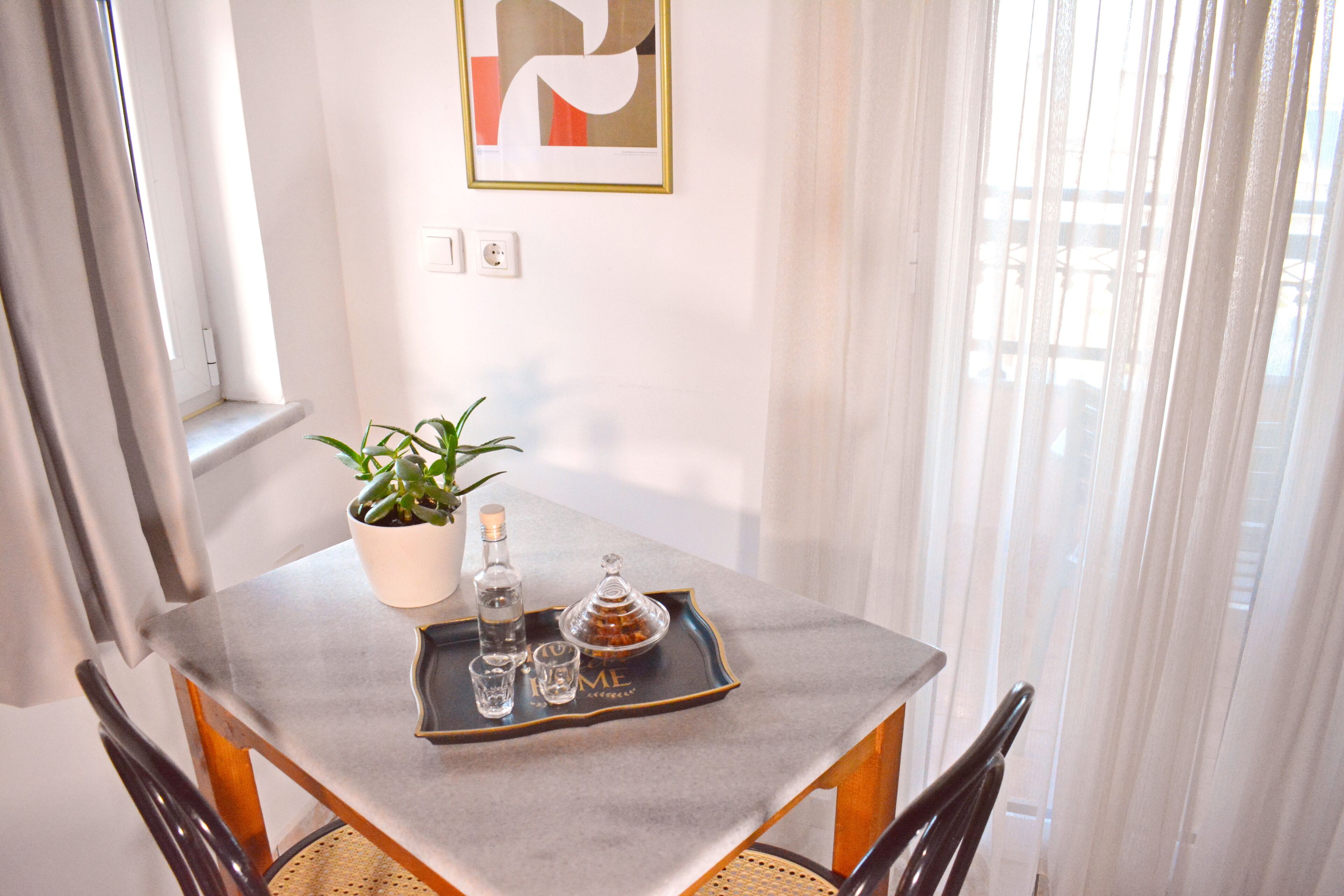 A dining table with a potted plant, a tray with bottles, and a decorative item.