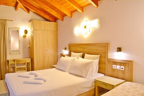 A hotel room with a wooden ceiling, a bed with white linens, a wooden wardrobe, a bedside table with a lamp, and a wall-mounted light fixture. - Melina's House (Chania)