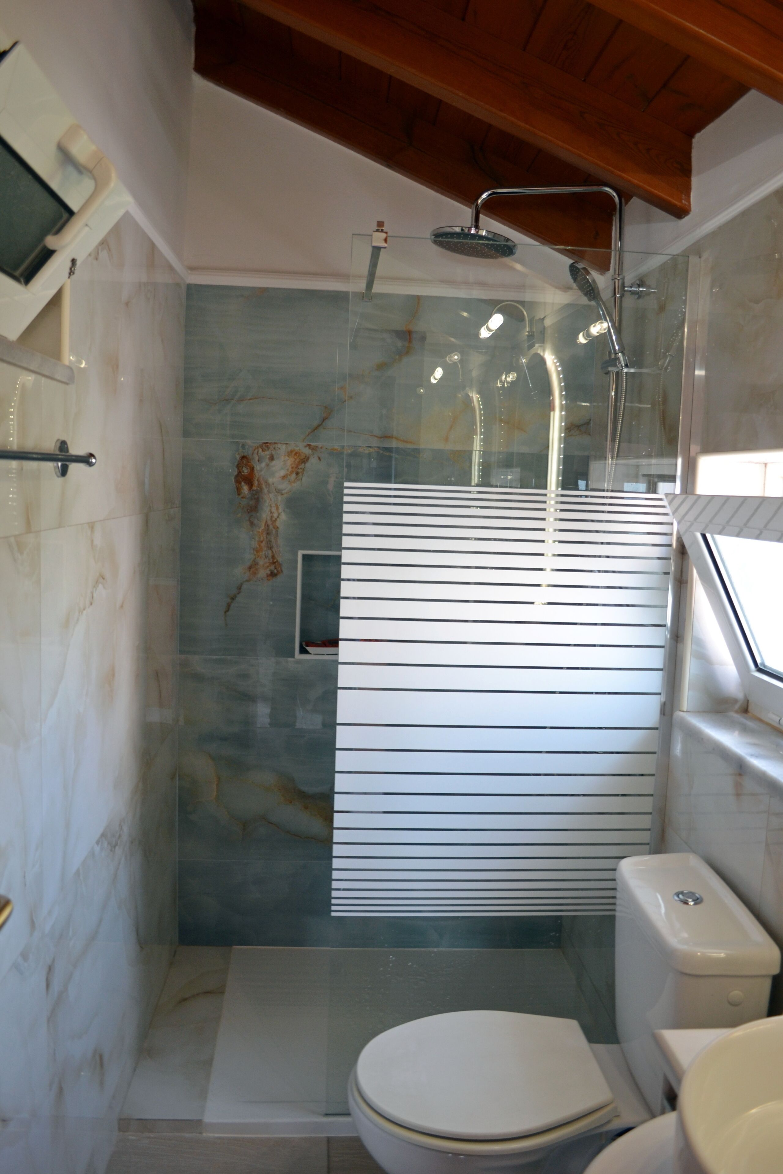 Un baño con ducha de vidrio, inodoro y lavamanos.