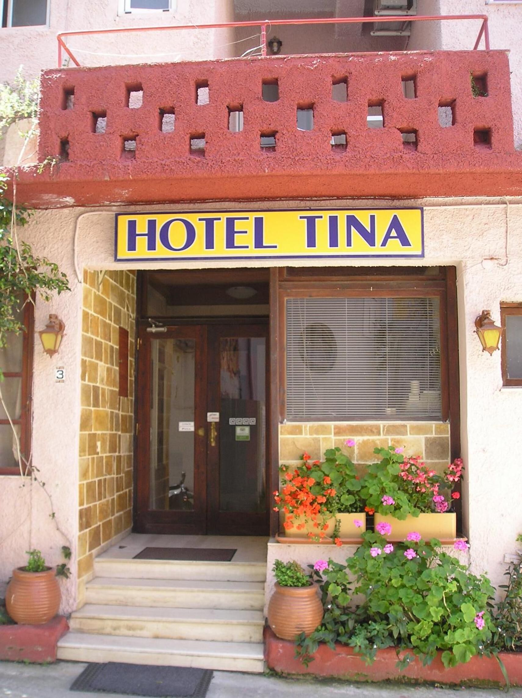 Entrada de un hotel con un cartel que dice 'HOTEL TINA'.