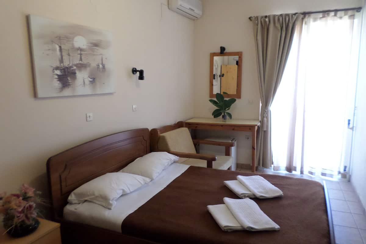 Habitación de hotel con una cama grande, un escritorio, una silla, un espejo y una ventana con cortinas.