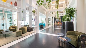 Un lobby amplio con techos altos, muebles modernos y plantas de interior.