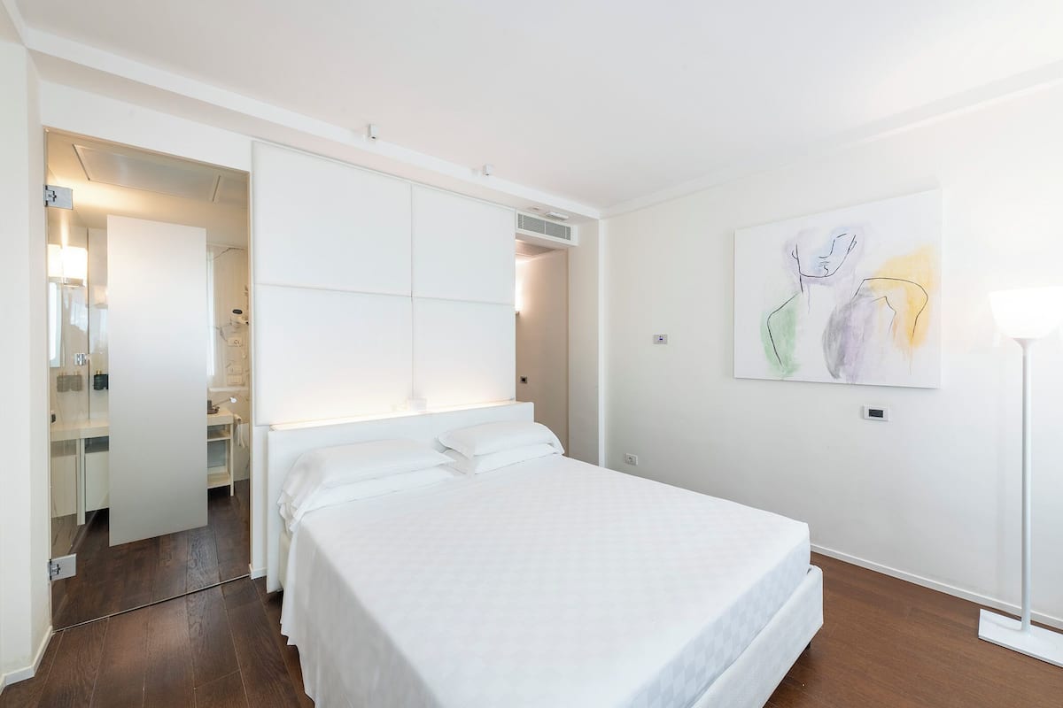 A bedroom with a bed, a wardrobe, and a painting on the wall.