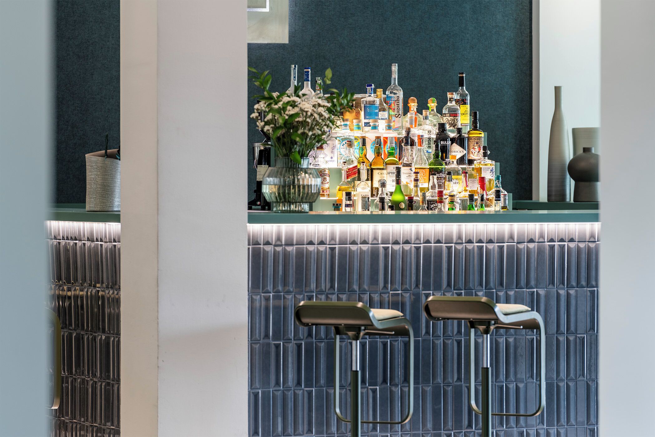 A bar area with a variety of liquor bottles and two bar stools.