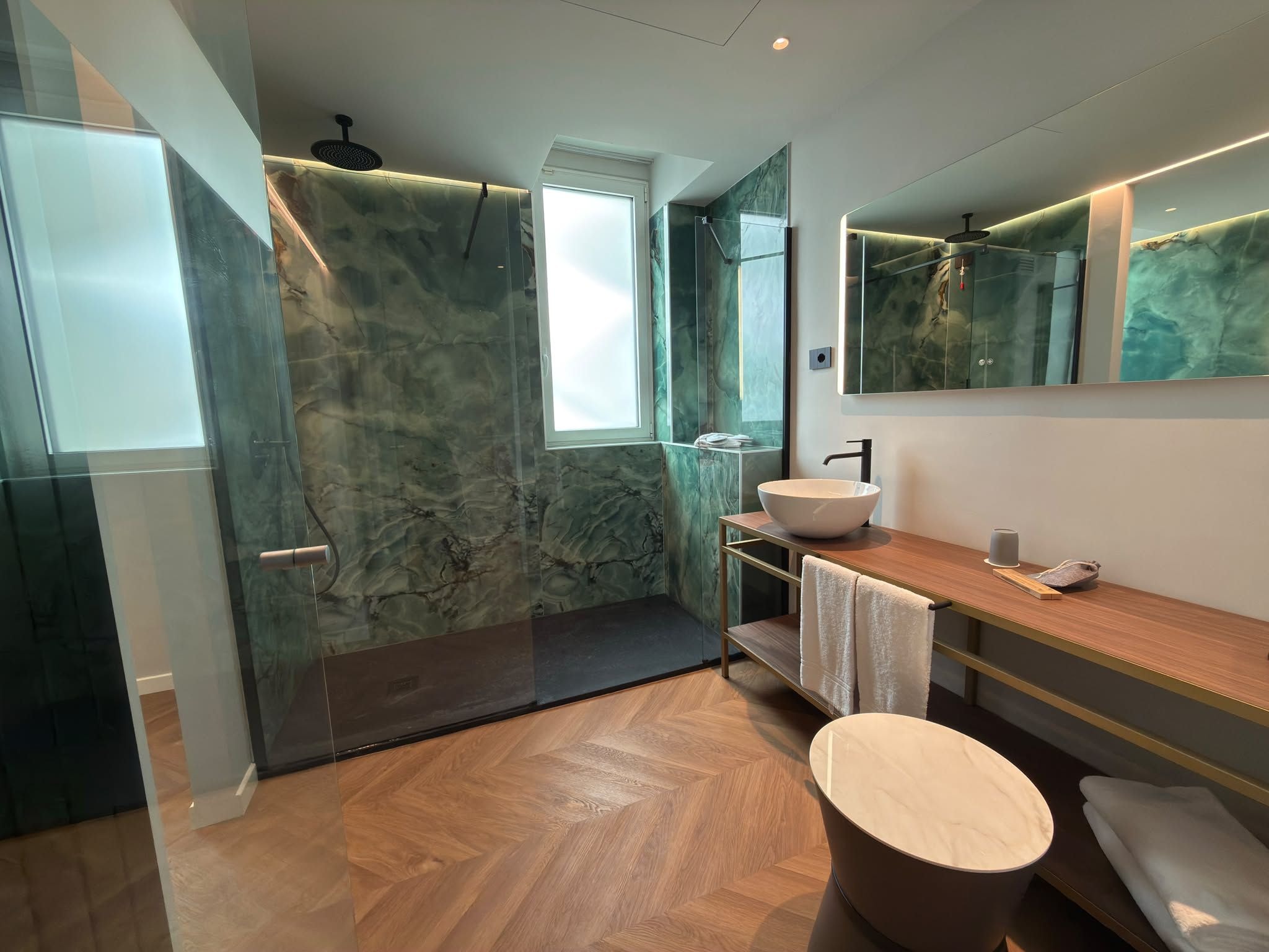 A modern bathroom with a glass shower enclosure, a freestanding sink, and a large mirror.