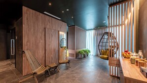 Un interior moderno con paneles de madera, una zona de estar con dos sillas de madera, un mostrador de recepción de madera con fruta y una lámpara, y una silla colgante.