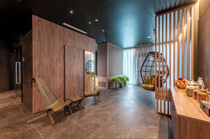 Un interior moderno con paneles de madera, una zona de estar con dos sillas de madera, un mostrador de recepción de madera con fruta y una lámpara, y una silla colgante.