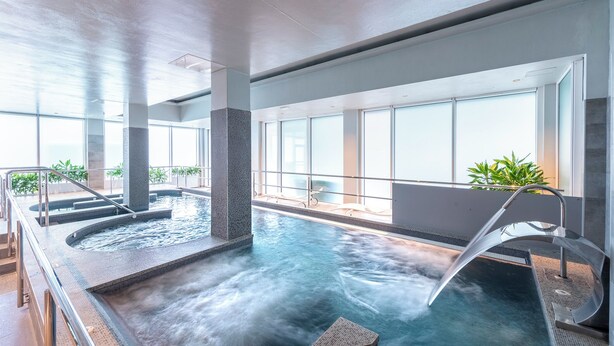 Una piscina interior moderna con agua cristalina, un jacuzzi y una zona de estar.