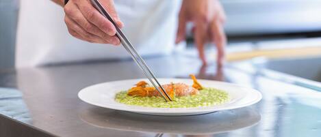 Un chef usando pinzas para servir un plato en un plato blanco.