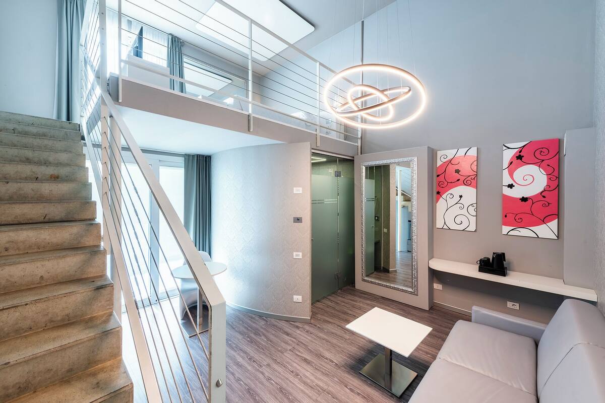 A modern interior with a staircase, a sofa, a coffee table, and artwork on the walls.