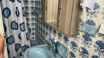 Ein Badezimmer mit blauem Waschbecken, Toilette und einer blauen Duschvorhang mit Avocado-Muster.