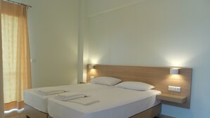 A neatly made bed with white linens and pillows, a wooden headboard, and bedside lamps.
