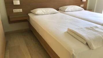 A double bed with a wooden headboard, two bedside tables with lamps, and a folded towel on the bed.