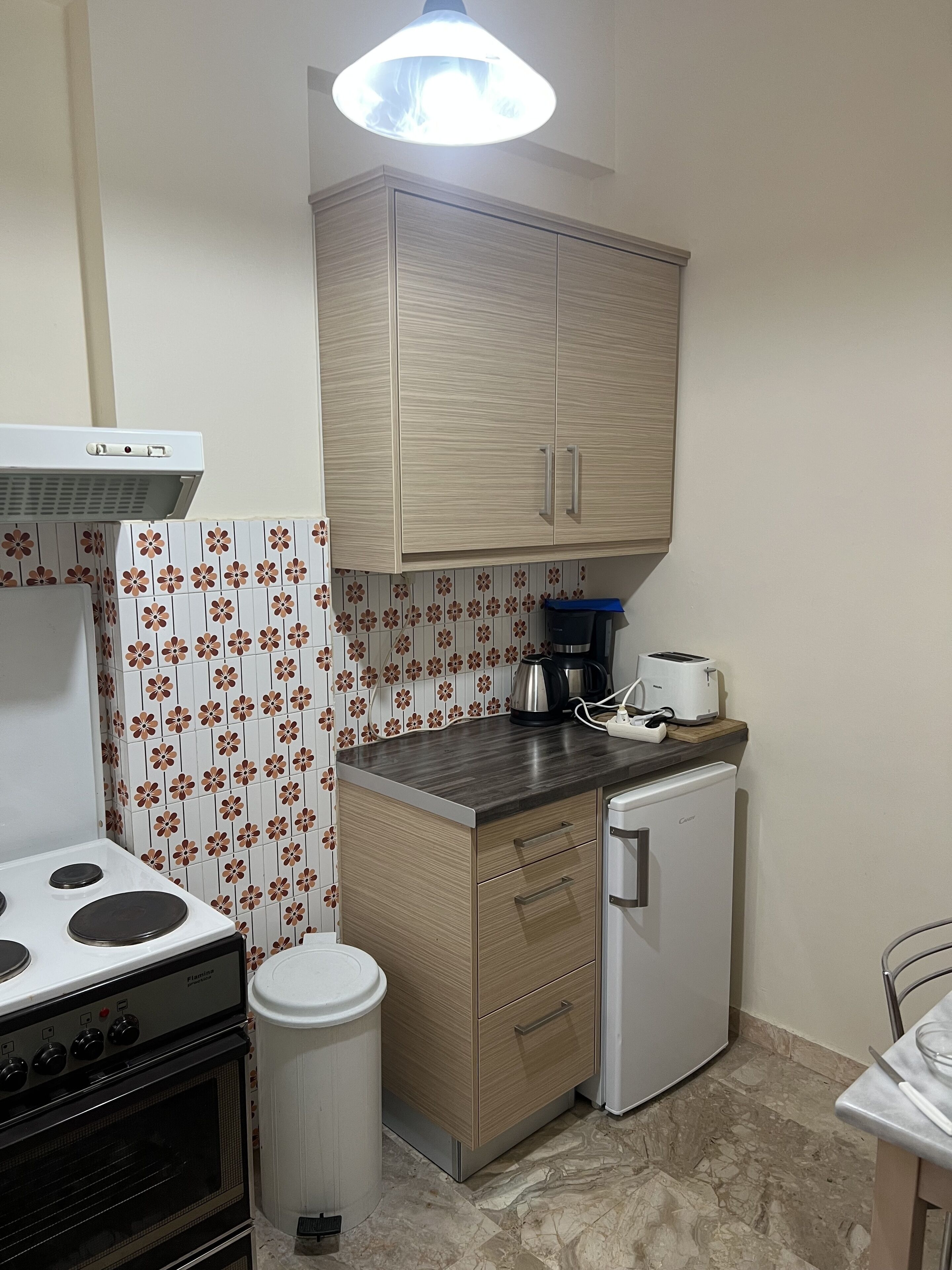 A compact kitchen with a stove, oven, refrigerator, and a small countertop with a toaster and coffee maker.