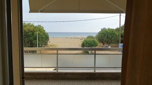 A view from a balcony overlooking a beach with umbrellas and a fence.