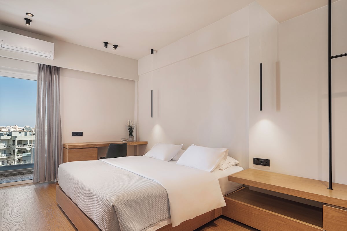A modern hotel room with a large bed, a wooden desk, and a view of the city.