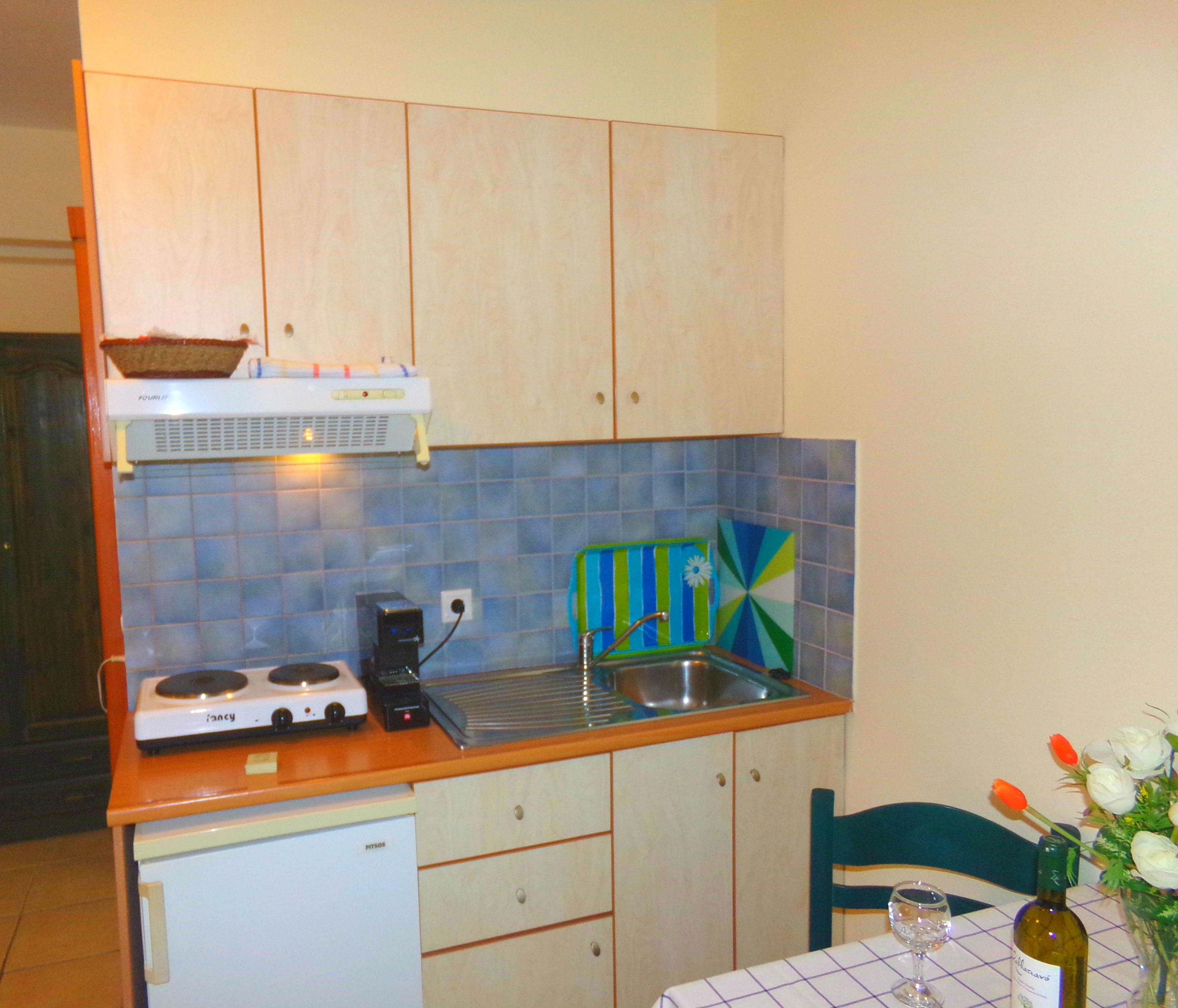 Una cocina compacta con estufa, lavamanos y un refrigerador pequeño.