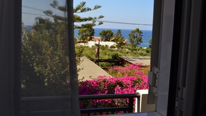 Une vue depuis un balcon doté d’une balustrade, donnant sur une zone côtière avec des bâtiments et un ciel dégagé.