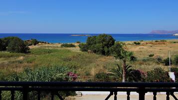 Un paisaje costero con vista al mar, una zona verde con árboles y un pueblo lejano.