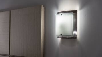 Lámpara de pared con panel de vidrio esmerilado, fijada en una pared con diseño de paneles de madera.