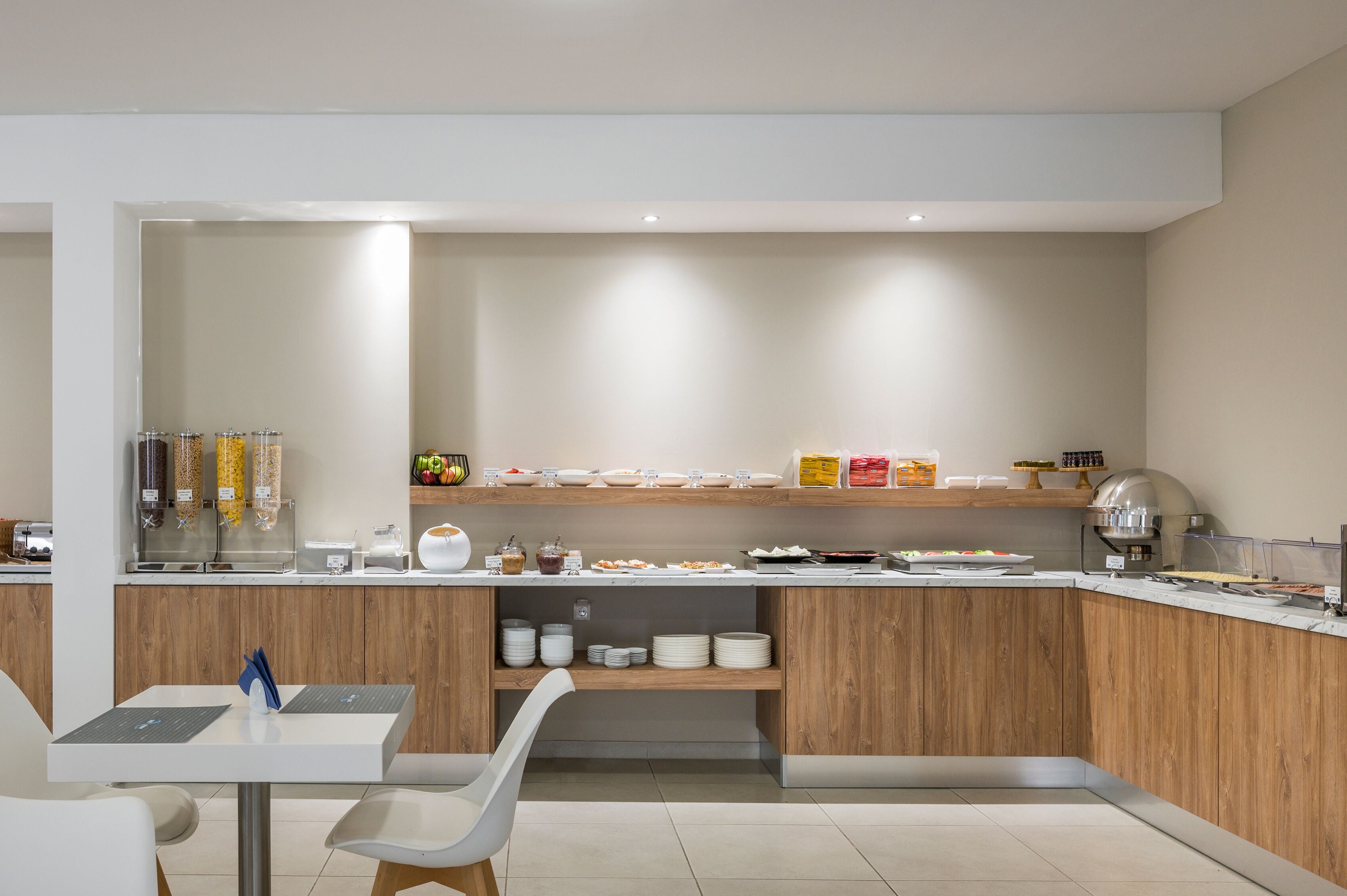 A modern kitchen with a wooden countertop, a coffee machine, and a variety of food items.