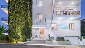 Un hôtel à plusieurs étages, doté d’une façade blanche, de balcons et d’un mur recouvert de lierre.