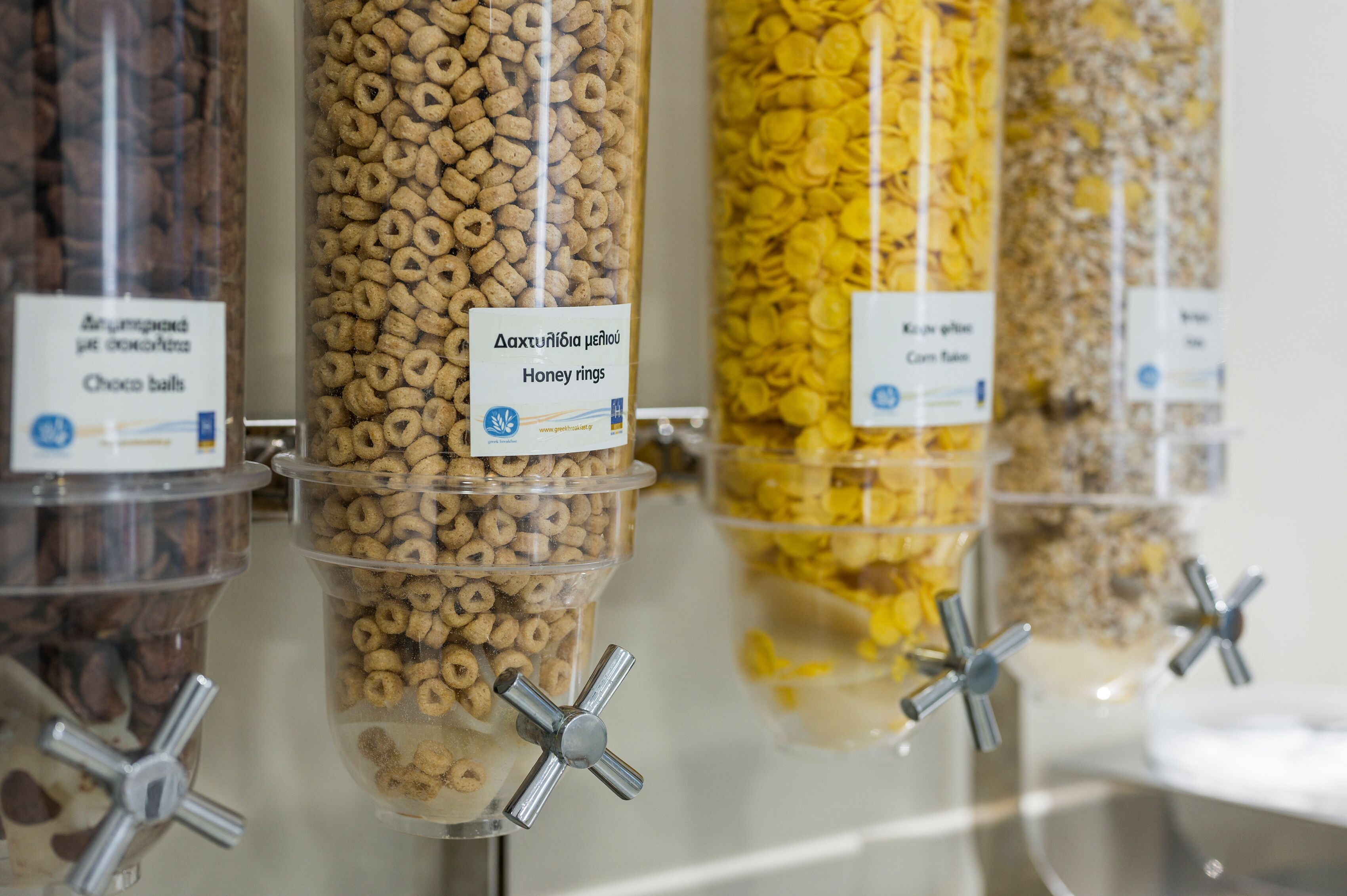 A row of cereal dispensers with labels in a foreign language.