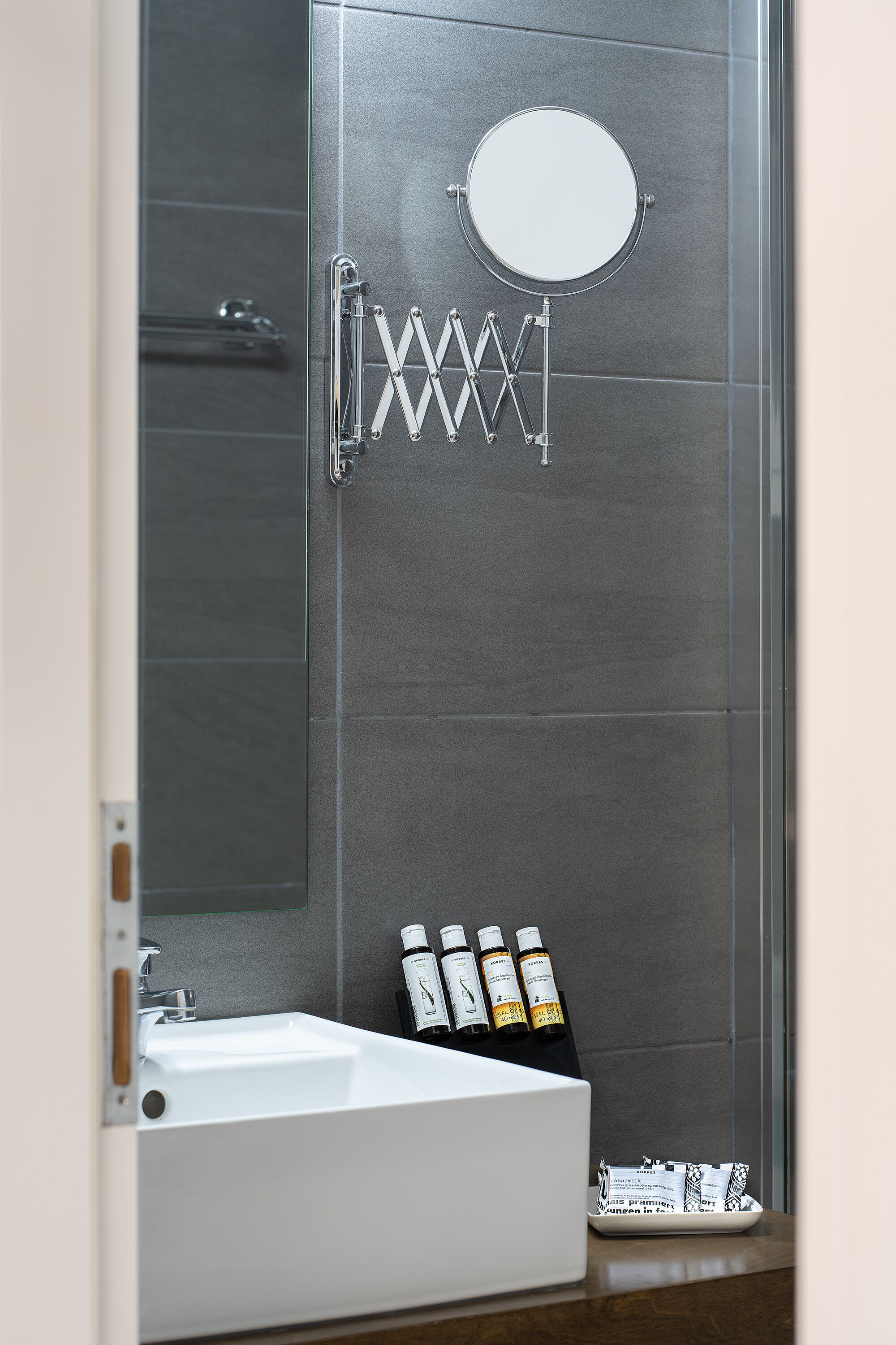 Un baño moderno con cabina de ducha de vidrio, un lavabo blanco y artículos de aseo en la encimera.