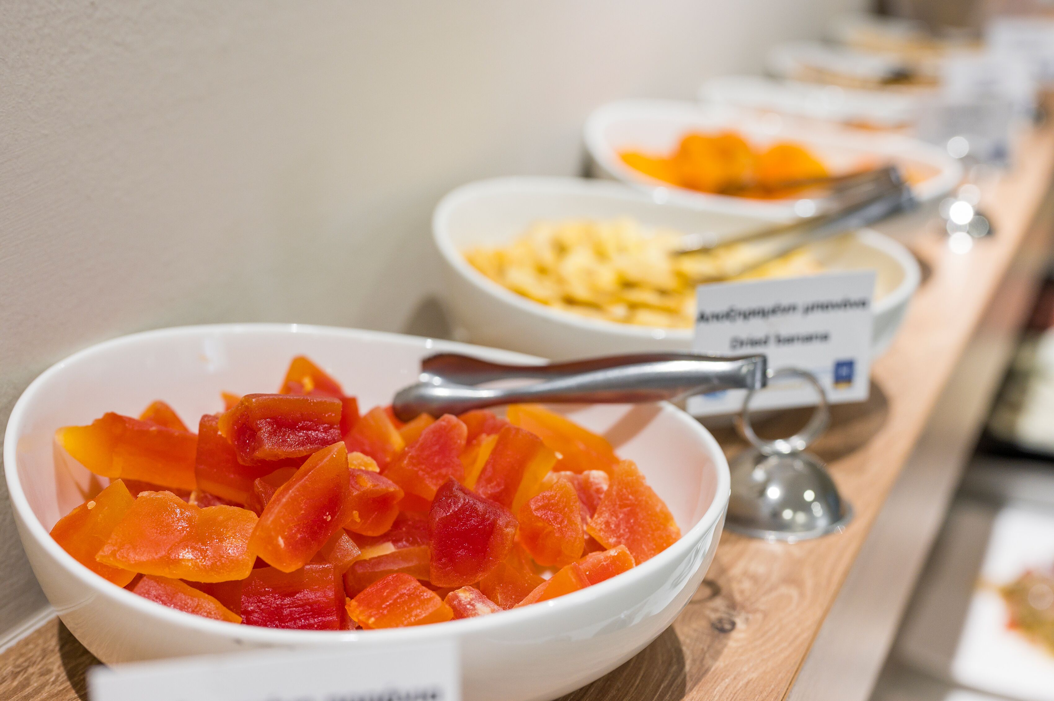 A buffet with various fruit options, including dried fruits and a bowl of sliced fruit.