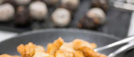 A close-up of fried dough sticks with a blurred background of other food items.