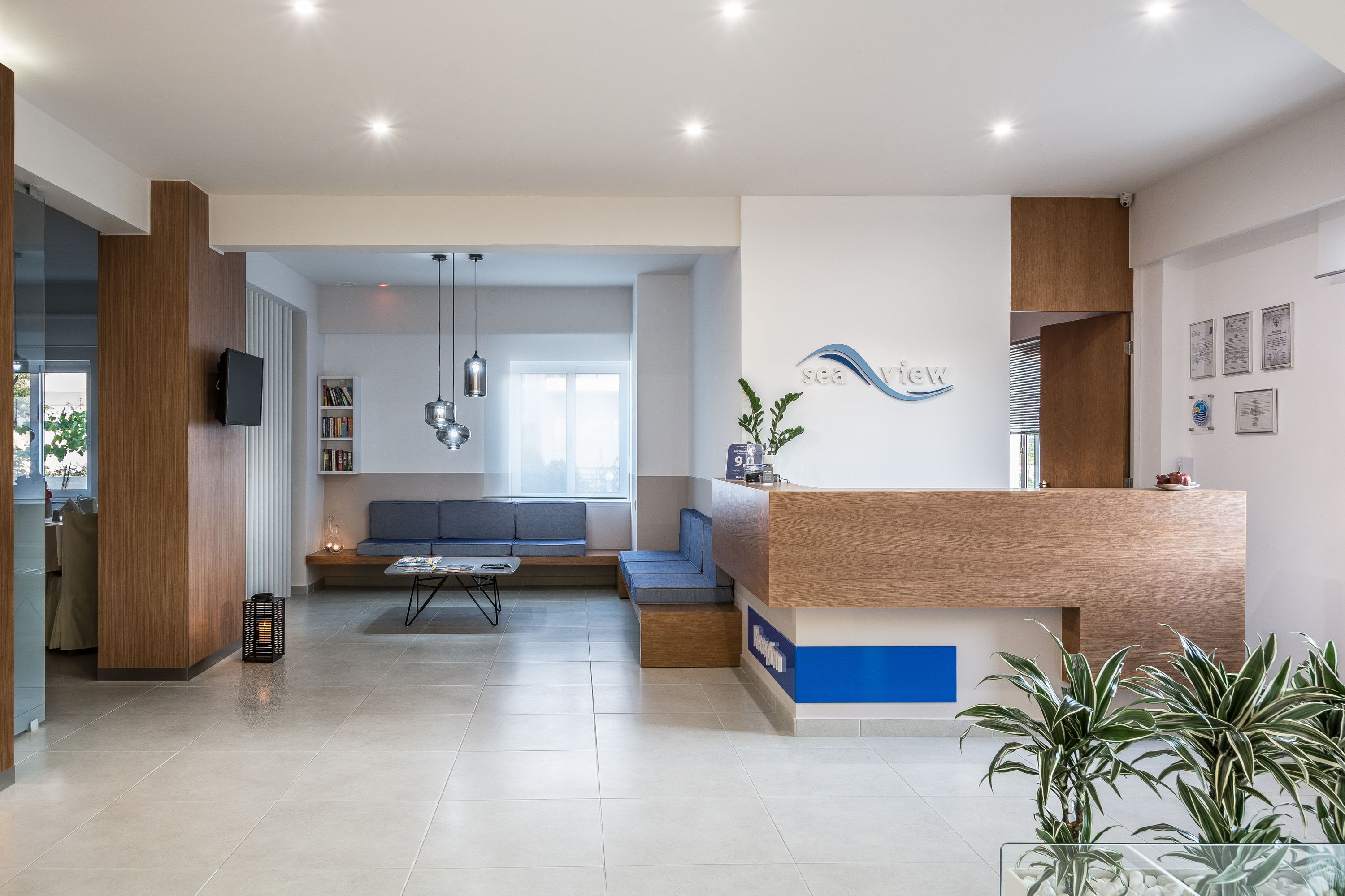 A modern reception area with a wooden reception desk, seating area, and a visible sign that reads "sea view".