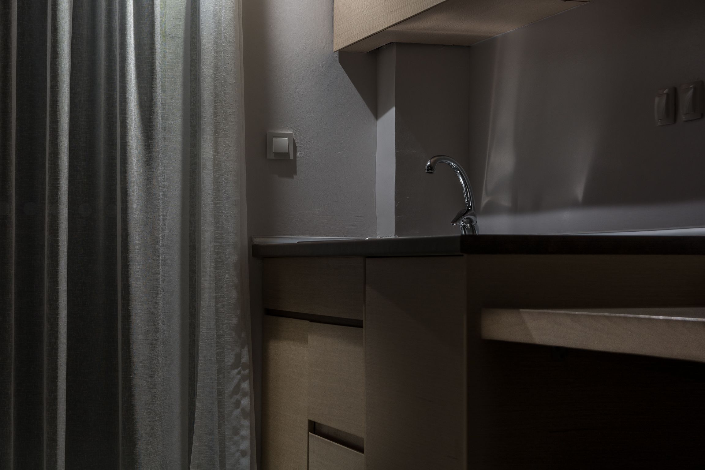 A modern kitchen with a stainless steel sink, a light switch, and a wooden countertop.
