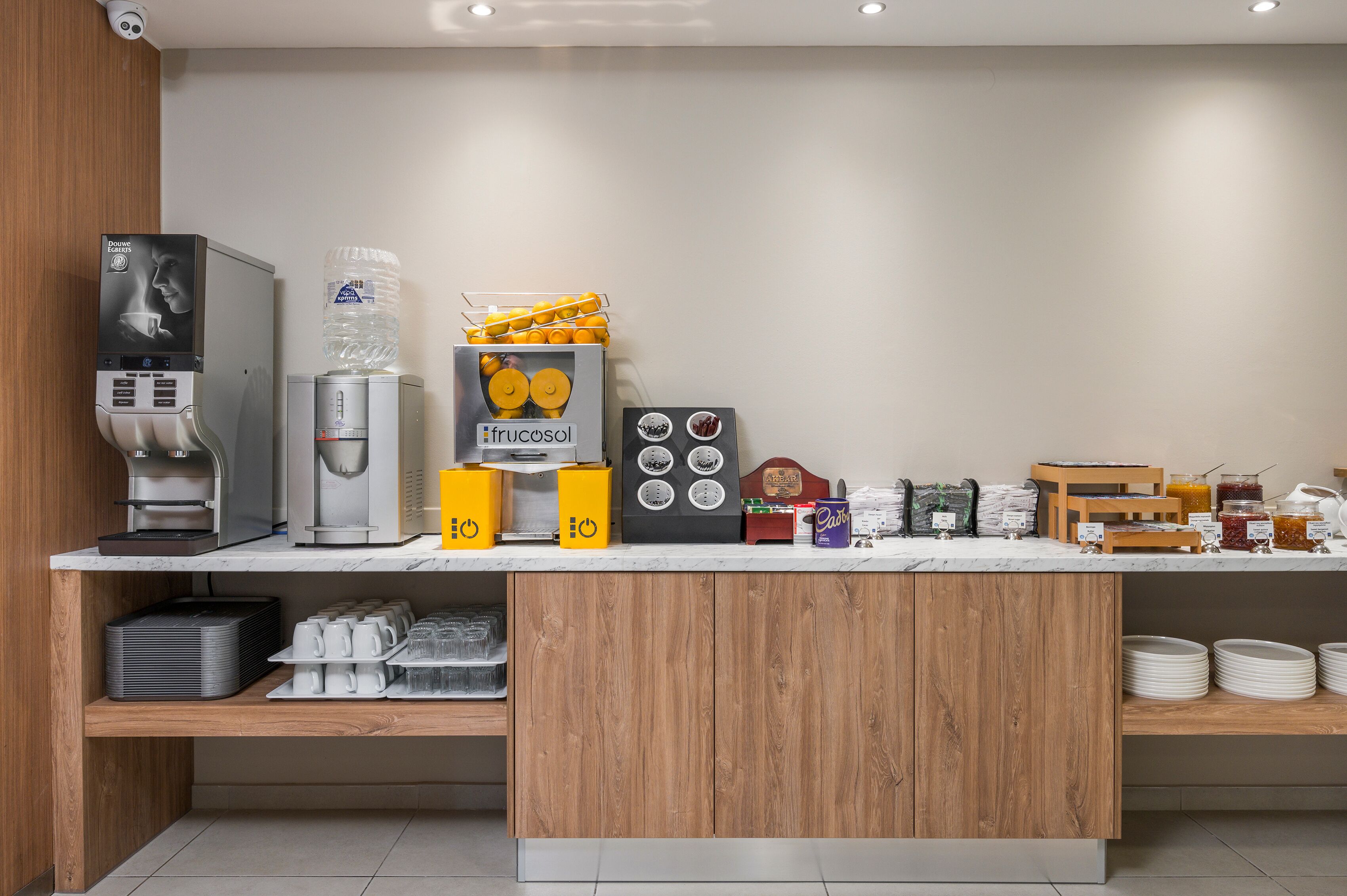 A modern breakfast bar with a coffee machine, water dispenser, and various food items.