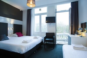 Habitación de hotel con una cama grande, una silla, un televisor y un balcón con vistas.