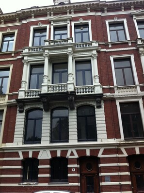 Un edificio de varios pisos con un estilo arquitectónico clásico, que presenta una fachada simétrica con ventanas distribuidas uniformemente y molduras decorativas.