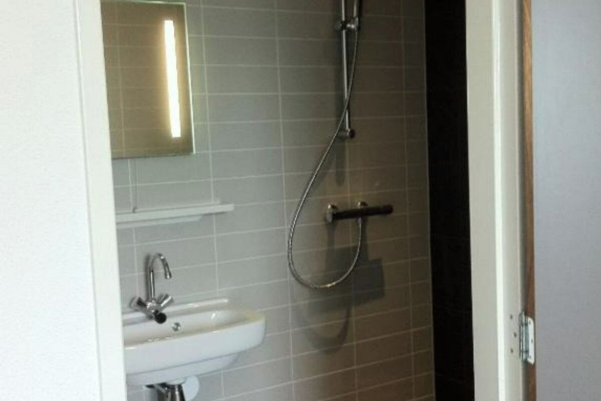 A bathroom with a sink, mirror, and shower.