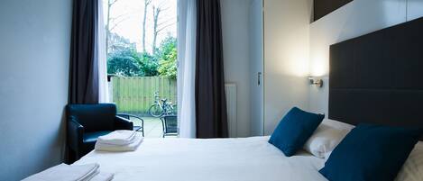 A hotel room with a large bed, two pillows, a chair, and a view of the outside.