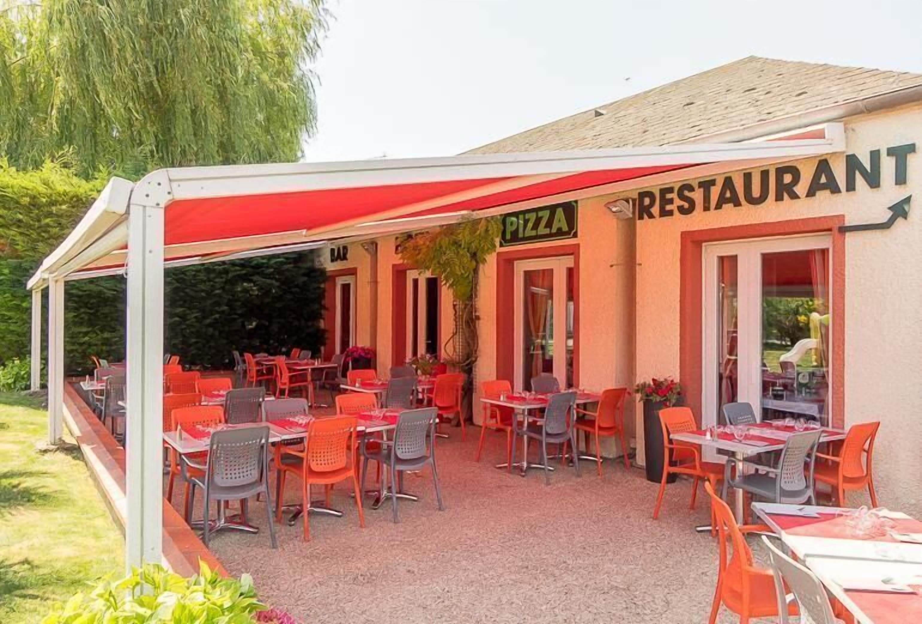 An outdoor restaurant with tables and chairs, a covered seating area, and a sign indicating the restaurant serves pizza.
