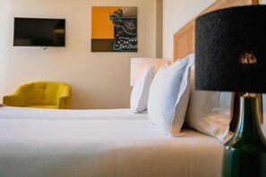 Ein Hotelzimmer mit einem Bett, einem gelben Sessel, einem Fernseher und einer Lampe.