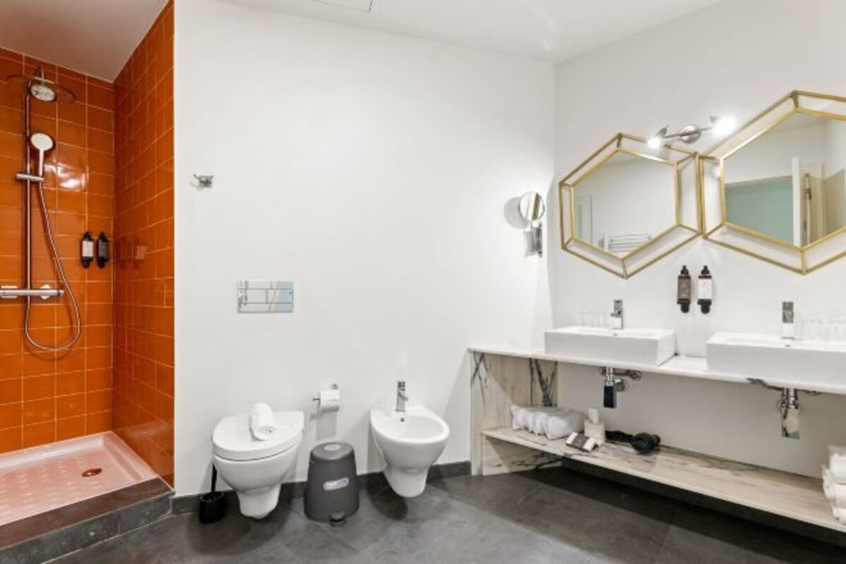A modern bathroom with a shower, toilet, bidet, and two sinks with mirrors.