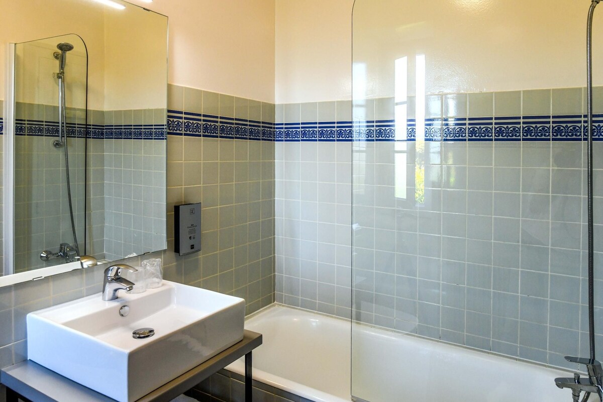 A bathroom with a glass-enclosed shower, a white sink, and a bathtub.