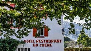 A hotel sign with "HOTEL RESTAURANT DU CHÈNE" written in red letters on a white wall.