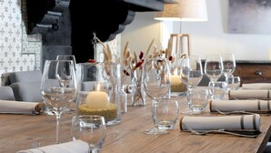 A dining table set with wine glasses, candles, and a piano in the background.