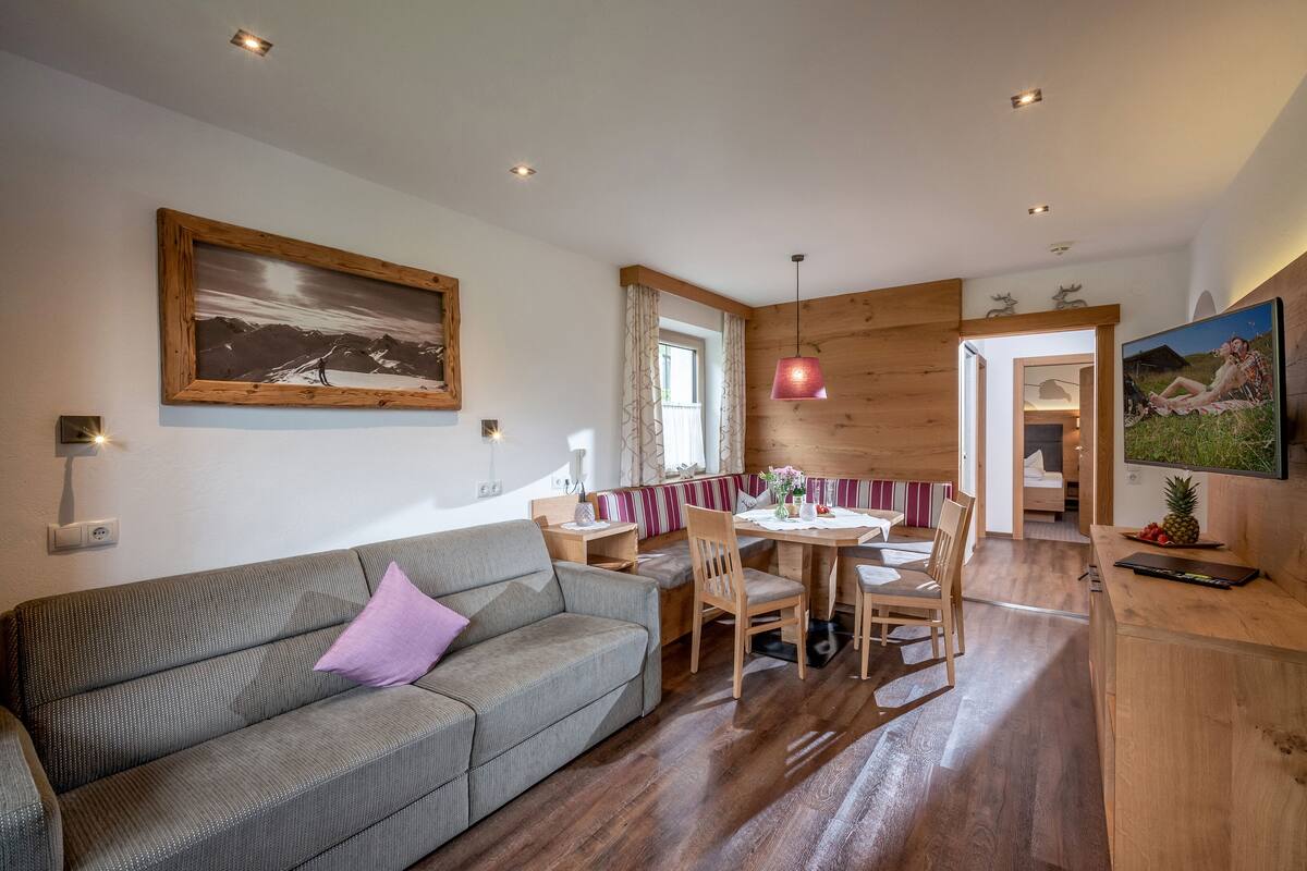 A cozy living area with a sofa, a dining table, and a wooden accent wall.