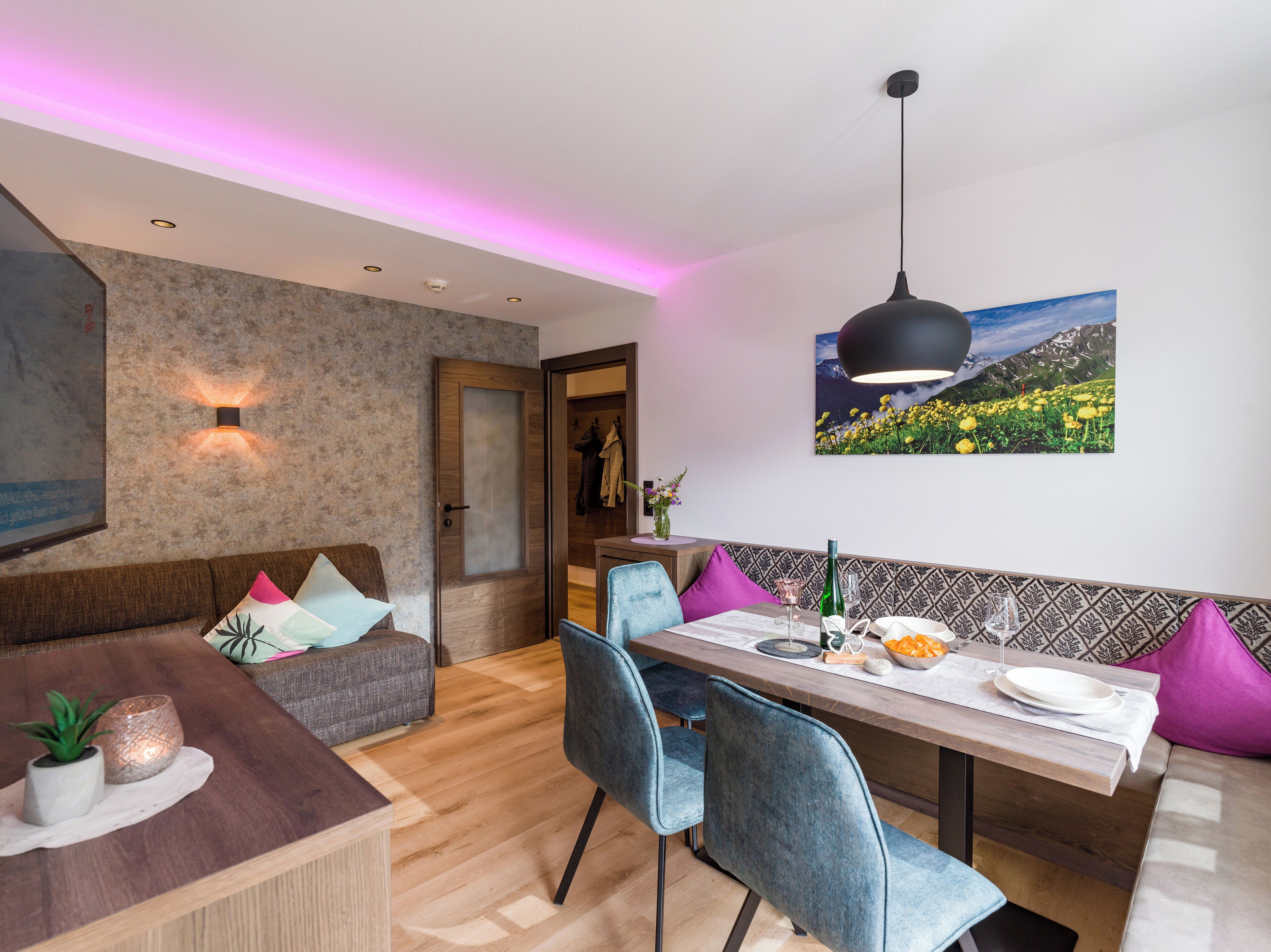 Un espace repas moderne avec une table en bois, des chaises bleues et un luminaire suspendu noir.