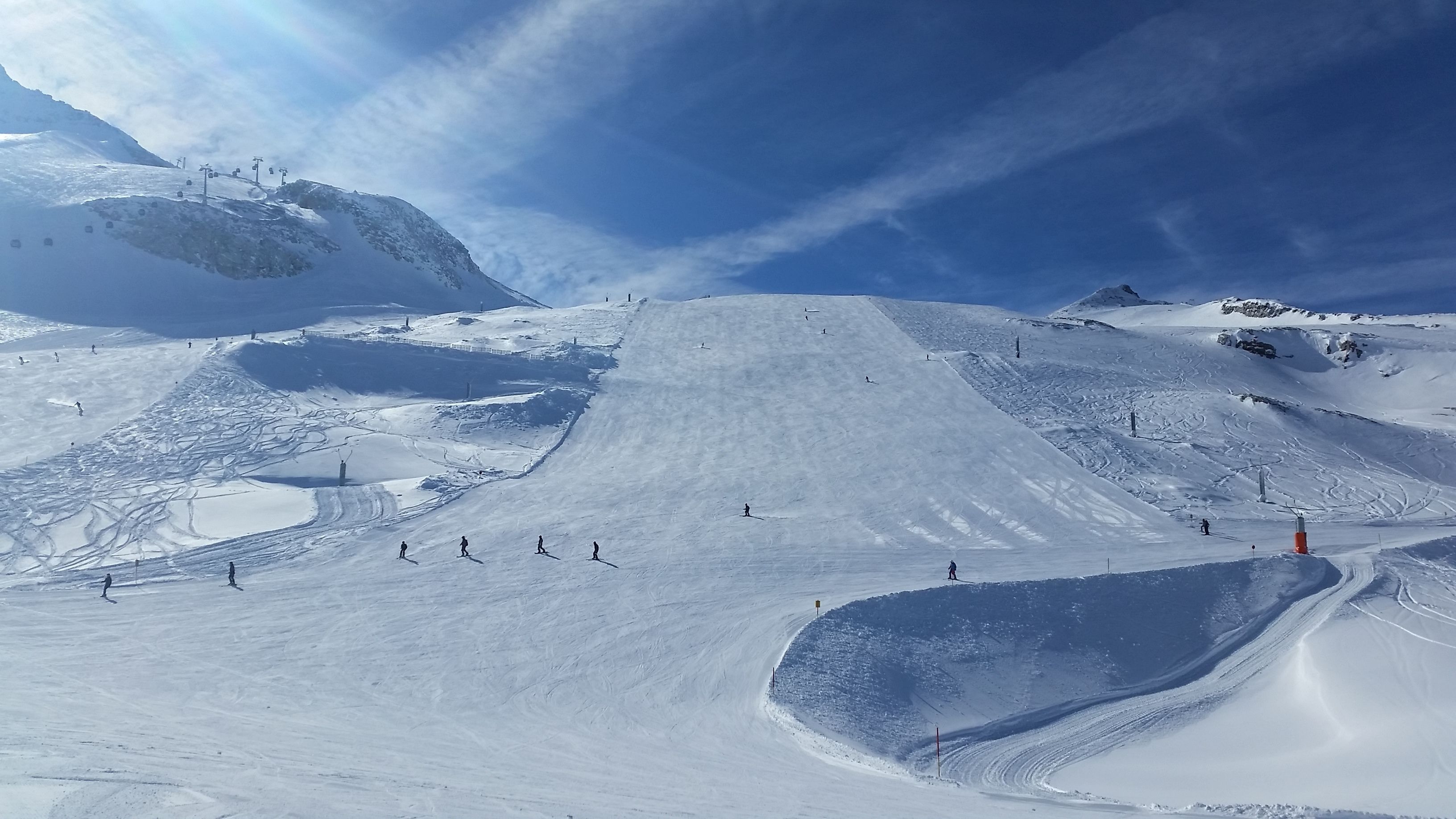 En sneklædt skibakke med en blød skråning og en skilift i baggrunden.