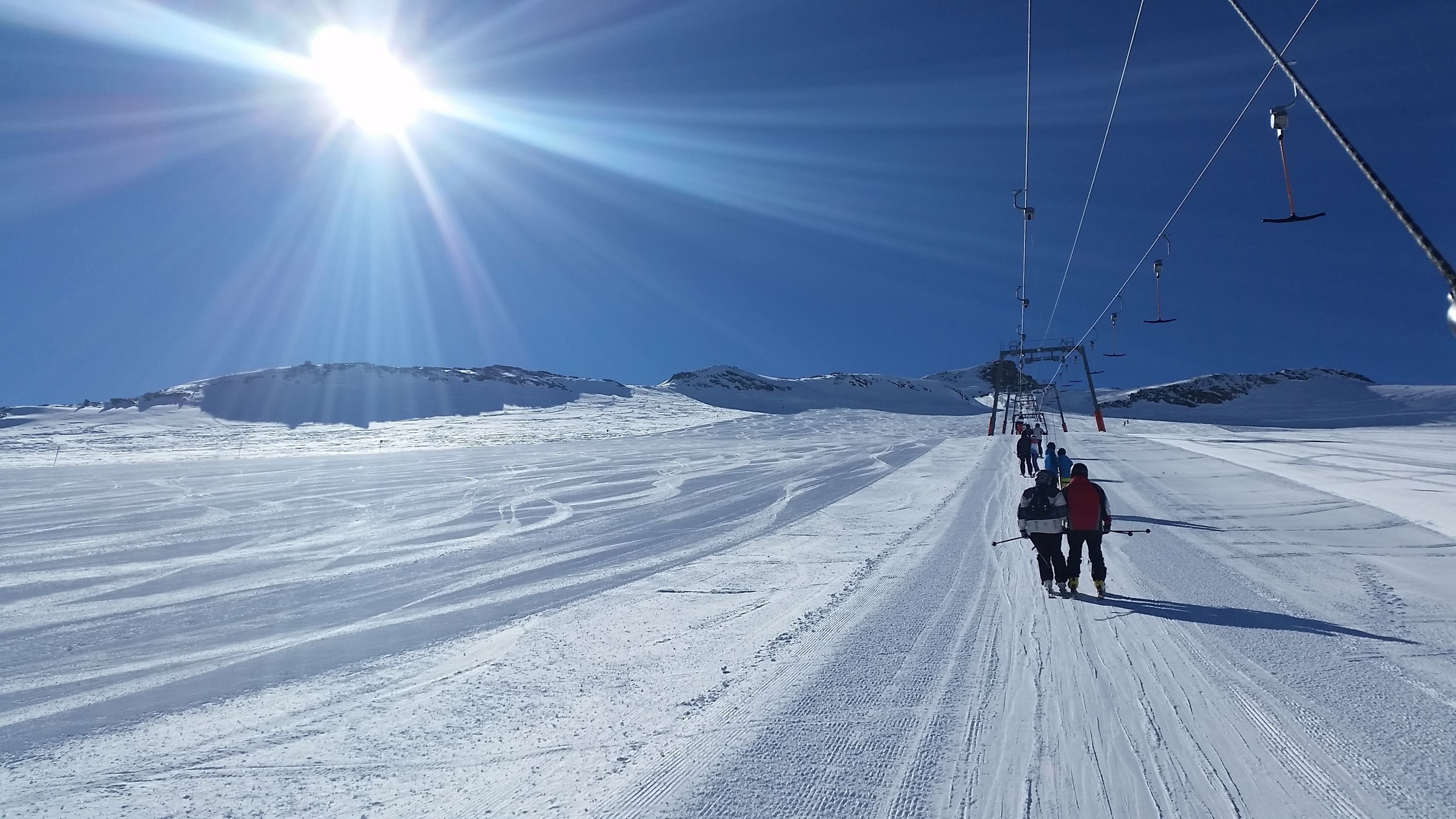 A snowy ski slope with skiers and a ski lift.