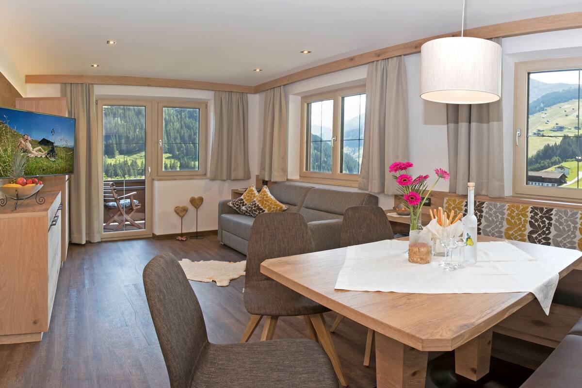 A cozy dining area with a wooden table, cushioned seating, and a scenic view through large windows.