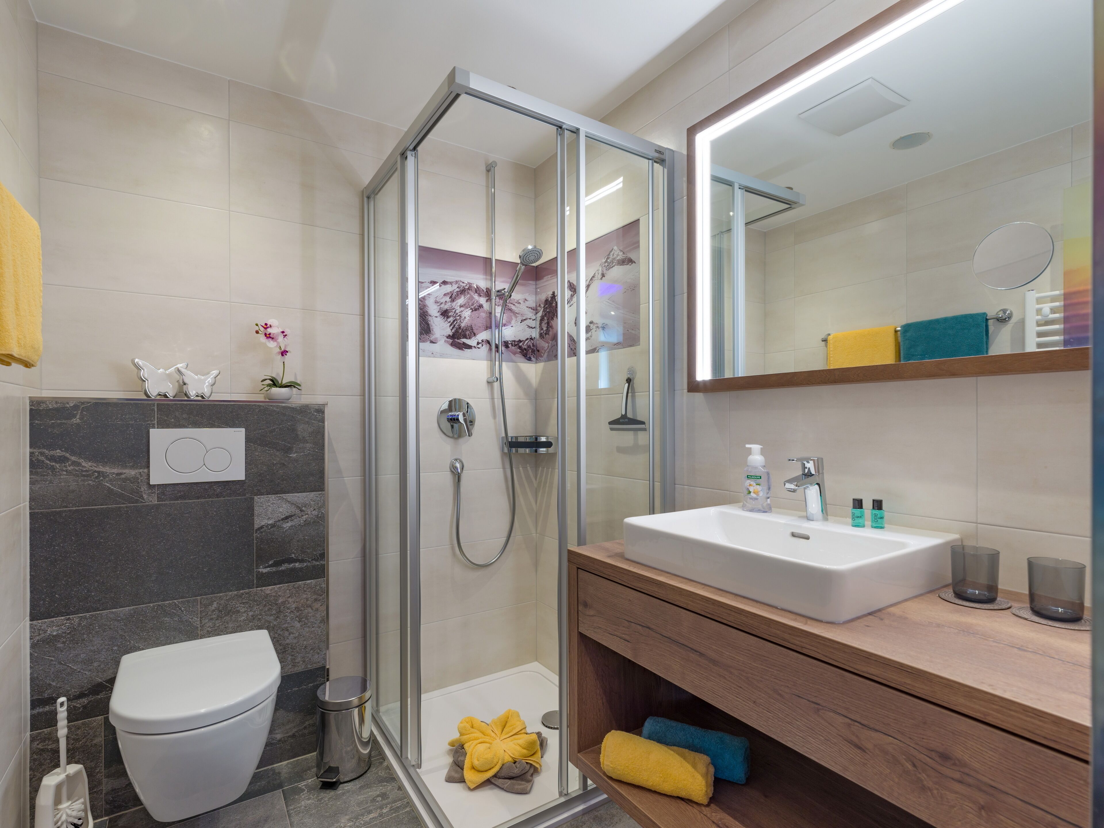 Une salle de bain moderne avec une douche à parois de verre, un lavabo blanc et un meuble-lavabo en bois.