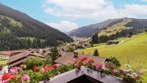 Un pueblo de montaña con casas tradicionales, cielo despejado y vistas al valle.